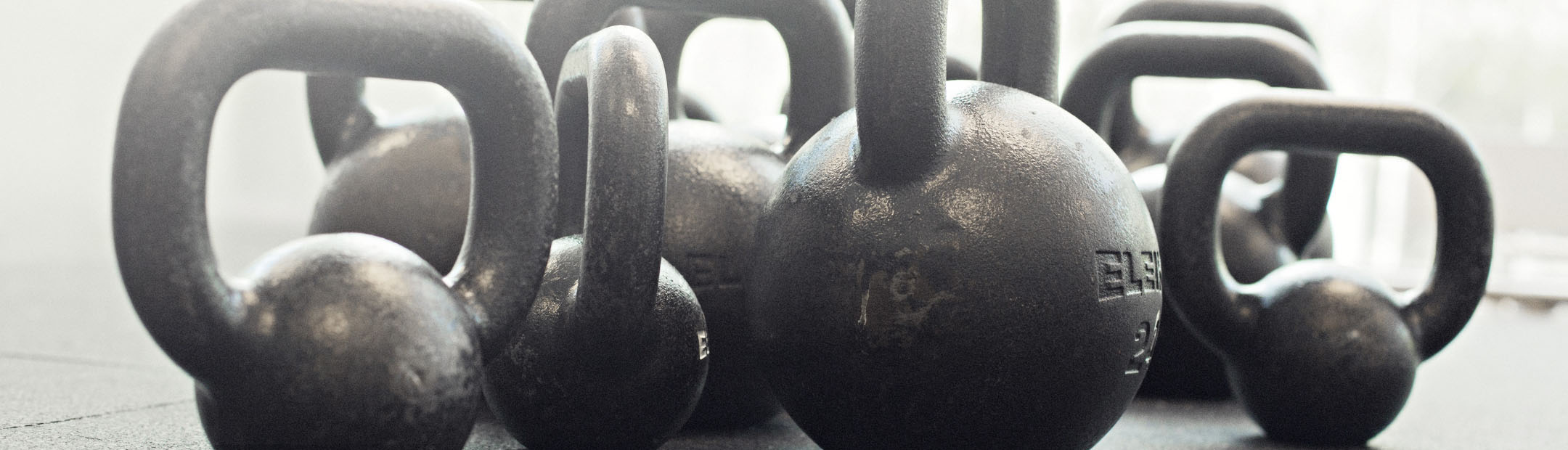 Närbild på svarta kettlebells i olika storlekar.